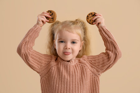 Funny little girl with cookies on beige backgroundの写真素材