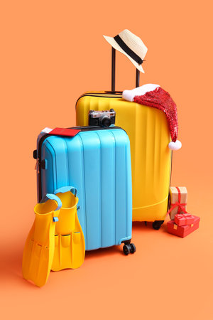Suitcases with beach accessories, Santa hat and Christmas gifts on color backgroundの写真素材