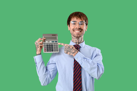 Handsome businessman in eyeglasses pointing at calculator on green backgroundの写真素材