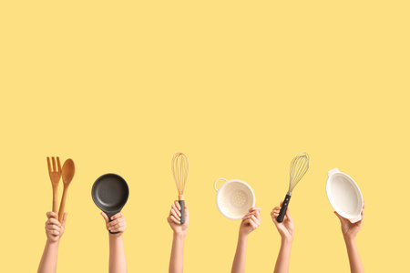 Female hands with different kitchen utensils on color backgroundの写真素材