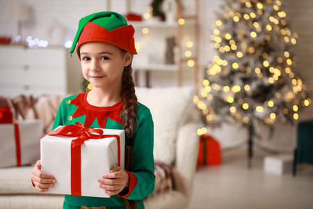 Cute little girl in elf costume with gift at home on Christmas Eve