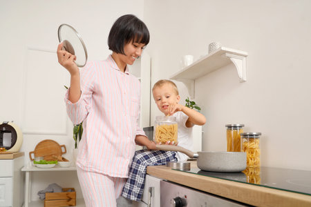 Young pregnant woman with her little son cooking pasta in kitchenの写真素材