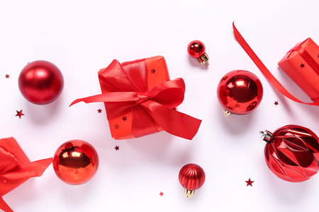 Red Christmas balls with gift boxes and confetti on white backgroundの写真素材