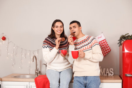 Young couple drinking hot cocoa with cookies in kitchen on Christmas Eveの写真素材