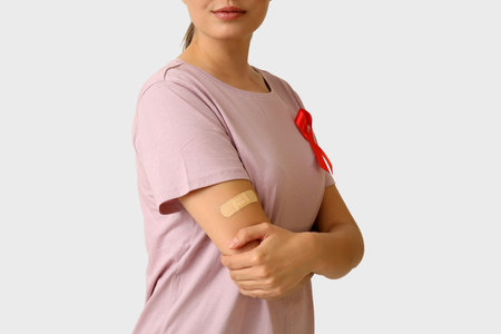 Woman with crossed arms and red ribbon on white background. AID awareness concept