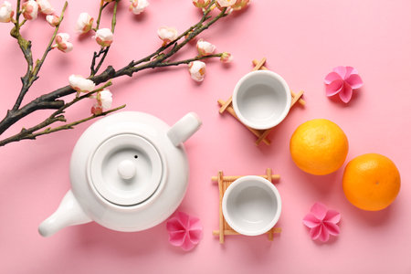 Teapot with cups, mandarins and sakura on pink background. Japanese New Year celebrationの写真素材