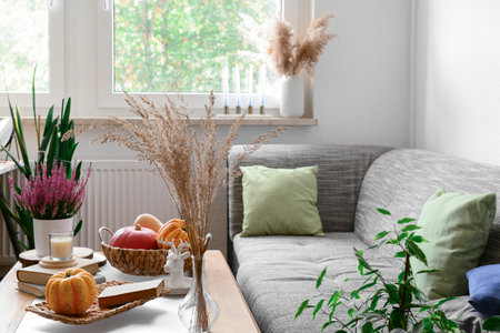 Cozy living room interior with sofa, coffee table, pumpkins and plants