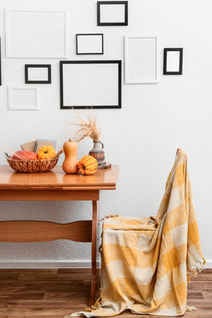 Interior of living room with wooden table, pumpkins, chair and blank photo frames on white wallの写真素材