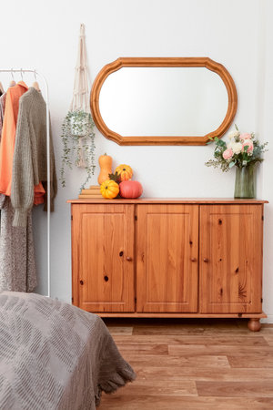 Interior of room with clothes rack, wooden cabinet, mirror and pumpkinsの写真素材