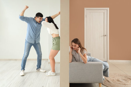 Young woman suffering from loud neighbors quarreling at homeの写真素材