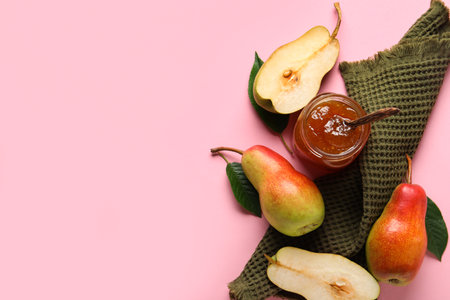 Glass jar of tasty pear jam with towel on pink backgroundの写真素材