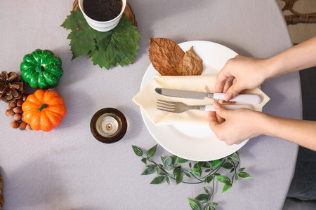 Woman placing cutlery on table with beautiful autumn serving
