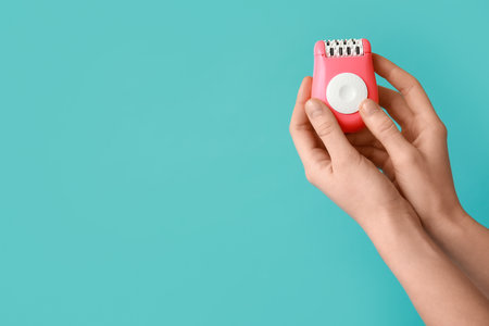 Female hands with modern elipator on turquoise backgroundの写真素材