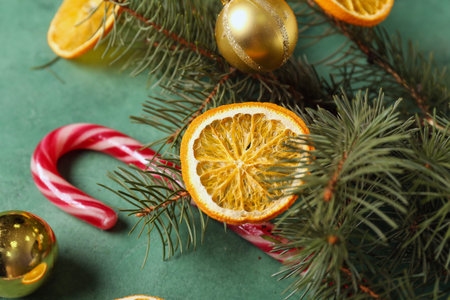 Dried orange slices with candy cane, fir branches and Christmas balls on green backgroundの写真素材
