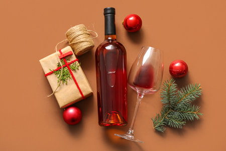 Bottle and glass of wine with Christmas gift box on brown backgroundの写真素材