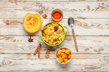 Pot of tasty millet porridge with pumpkin and honey on white wooden backgroundの写真素材