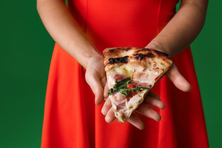 Beautiful young woman with slice of tasty pizza on green background, closeup