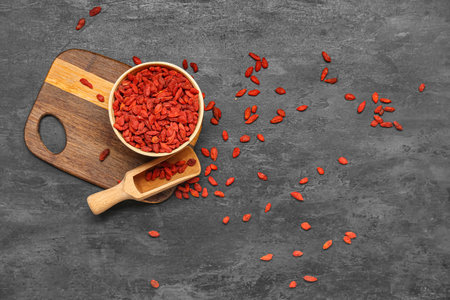 Bowl and scoop with red dried goji berries on black backgroundの写真素材