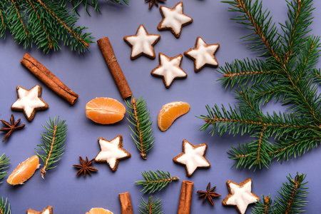 Star-shaped gingerbread cookies with mandarin, cinnamon and fir branches on blue background