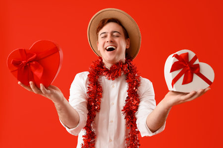 Young man with gifts on red background. Valentine's Day celebration