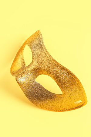 Shiny golden carnival mask for Mardi Gras celebration on yellow backgroundの写真素材