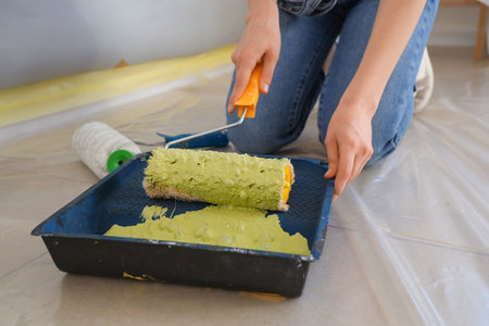 Young woman with paint roller doing repairs in room, closeupの写真素材