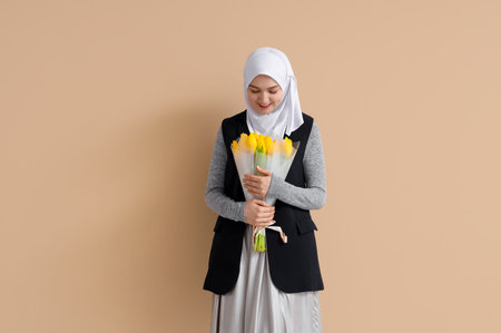 Young Muslim woman with tulips on beige background. Ramadan celebrationの写真素材