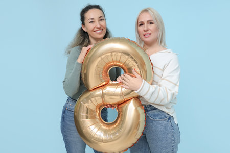 Mature women with golden air balloon in shape of figure 8 on blue background. International Women's Dayの写真素材