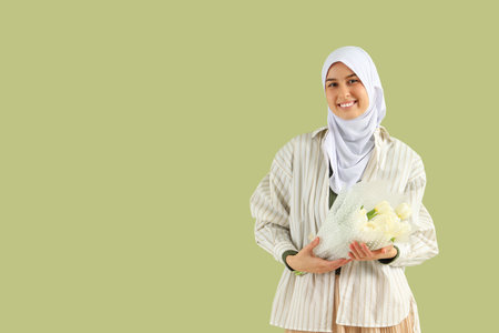 Young Muslim woman with tulips on green background. Ramadan celebrationの写真素材