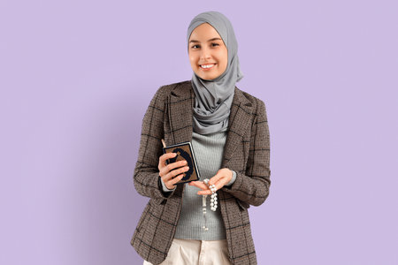 Young Muslim woman with Koran and praying beads on lilac background. Ramadan celebrationの写真素材