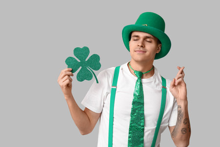 Young man in leprechaun's hat and with shamrock crossing fingers on light background. St. Patrick's Dayの写真素材
