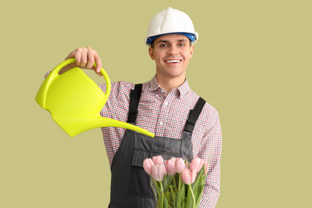 Male worker with tulips and watering can on green background. International Women's Day celebrationの写真素材