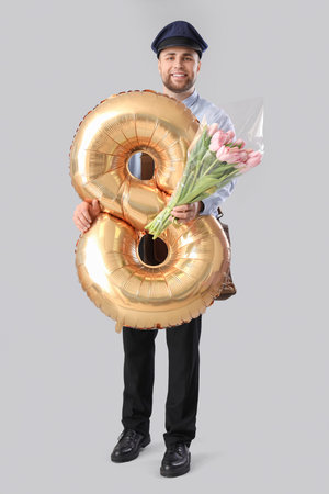 Handsome postman with tulips and balloon in shape of figure 8 on light background. International...