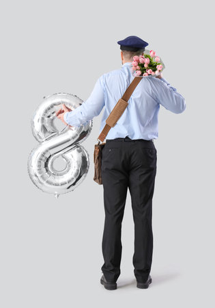 Handsome postman with tulips and balloon in shape of figure 8 on light background, back view....