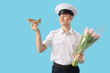 Male pilot with tulips and wooden airplane on blue background. International Women's Day celebrationの写真素材
