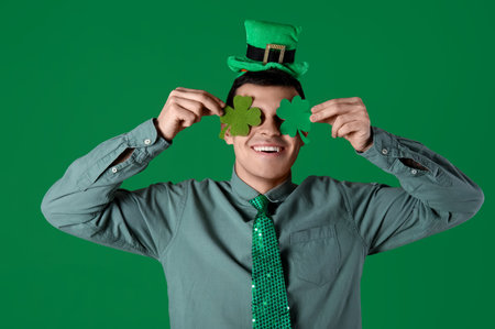 Happy young man with clovers on green background. St. Patrick's Dayの写真素材