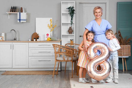 Little children and their grandmother with balloon in shape of figure 8 at home. International...