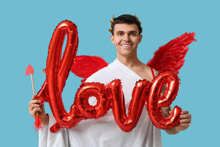 Young man dressed as Cupid with arrow and word LOVE made of balloons on blue background. Valentine's...