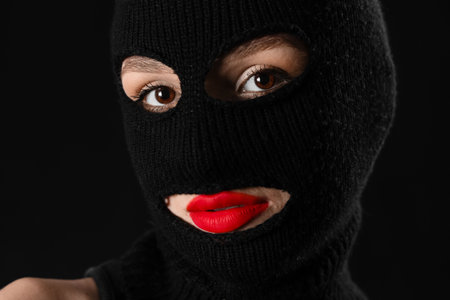 Beautiful young stylish woman in balaclava on black backgroundの写真素材