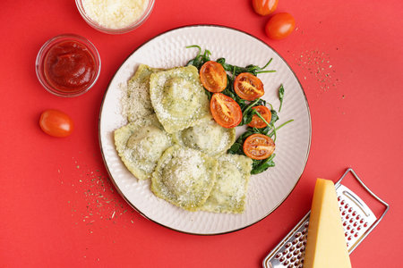 Plate of tasty ravioli with tomatoes and cheese on red backgroundの写真素材