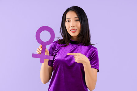 Young Asian woman pointing at gender symbol on lilac backgroundの写真素材