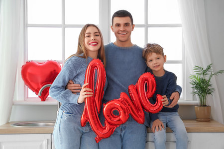 Little boy with his parents and the word LOVE made of balloons in kitchen on Valentine's Dayの写真素材
