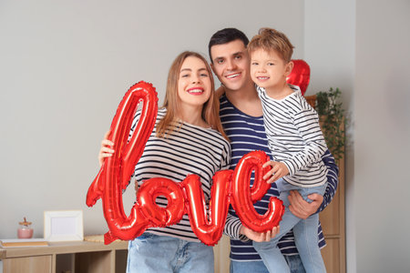Little boy with his parents and word LOVE made of balloons at home on Valentine's Dayの写真素材