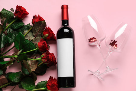 Bottle of wine with glasses and roses on pink background. Valentine's Day celebrationの写真素材
