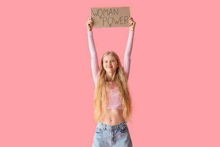 Young girl holding paper with text WOMAN POWER on pink background