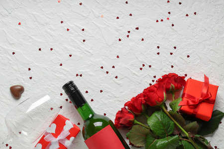 Bottle of wine with glass, gift boxes, chocolate candy and red roses on white background. Valentine's Day celebrationの写真素材