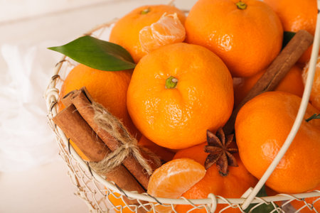 Basket of sweet mandarins with cinnamon and star anise on white wooden tableの写真素材