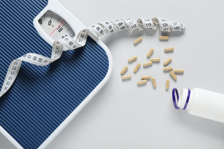 Scales, measuring tape and capsules on gray background, closeupの写真素材