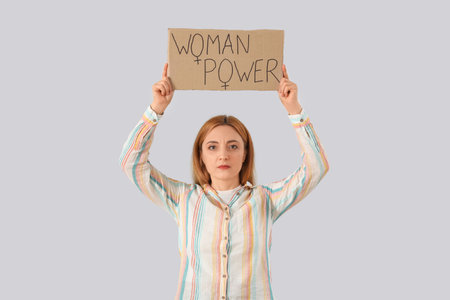 Mature woman holding paper with text WOMAN POWER on light backgroundの写真素材