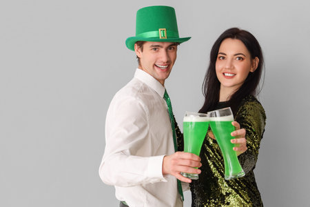 Young couple with beer on light background. St. Patrick's Day celebration